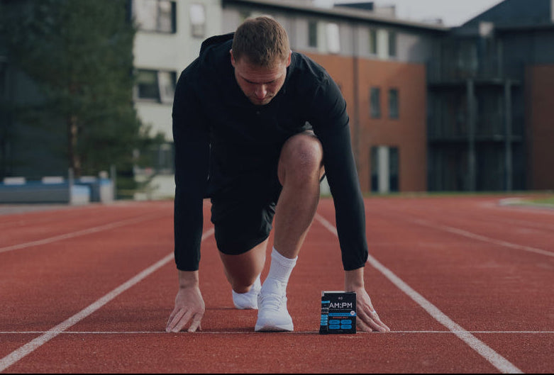 Man on a running track with a supplement container in front of him