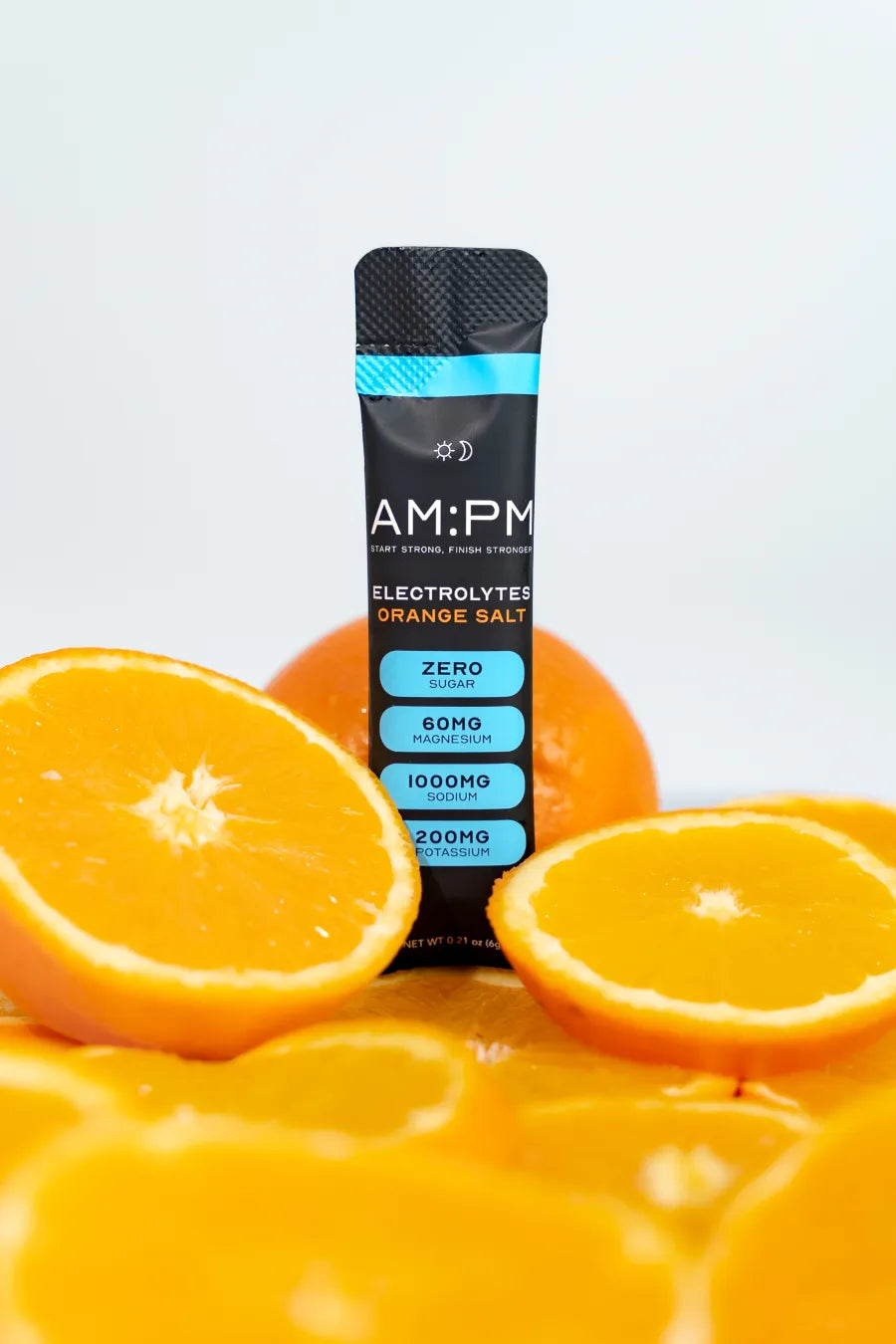 An AM:PM Orange Salt electrolyte sachet with fresh orange halves and slices